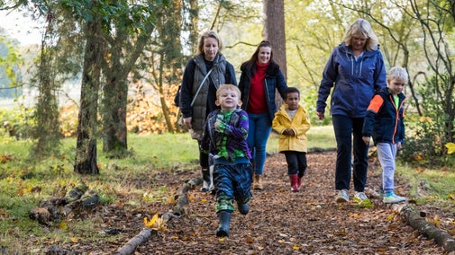 Parents and children walking along an autumnal path in the woods